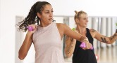 Two women take part in an exercise class holding dumbbells.